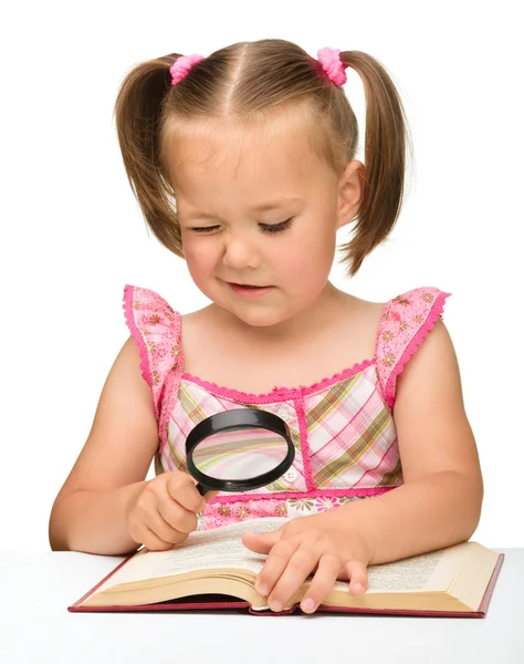 Malá dívka hra s knihou a Lupa — Stock fotografie