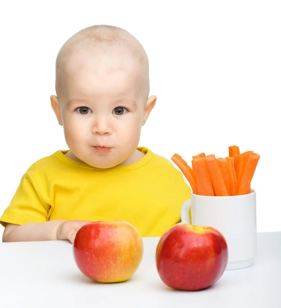 Ładny chłopczyk zjada marchewki i jabłka — Zdjęcie stockowe