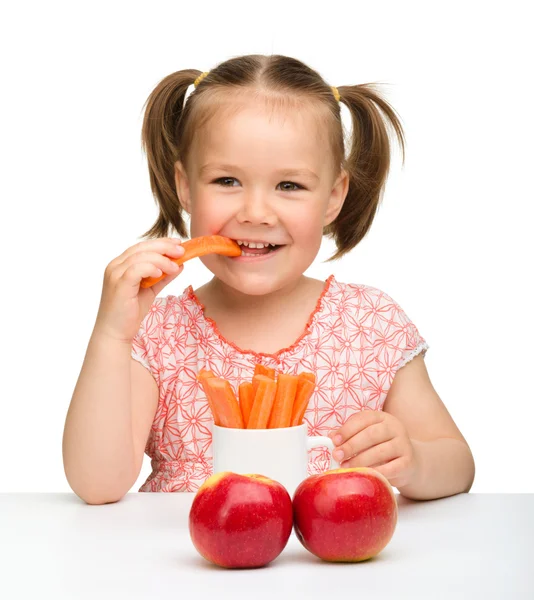 Cute little girl eats carrot and apples — Stock Photo, Image