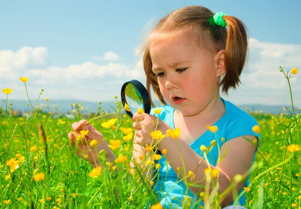 Kleines Mädchen untersucht Blumen mit Lupe — Stockfoto