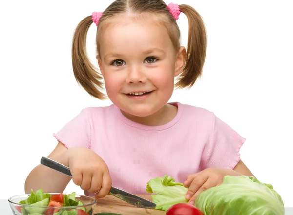 Pikkutyttö leikkaa porkkanaa salaatiksi. — kuvapankkivalokuva