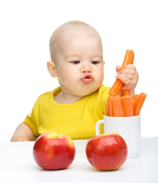 Kleiner Junge zieht Karotte aus einer Tasse — Stockfoto