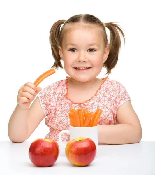 Sevimli küçük kız havuç ve elma yiyor. — Stok fotoğraf