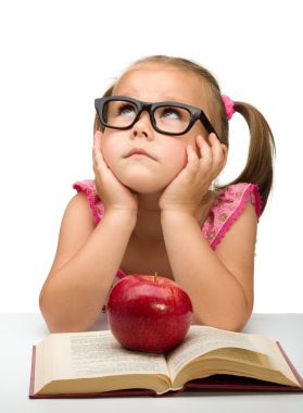 Little girl is sitting bored with a book clipart