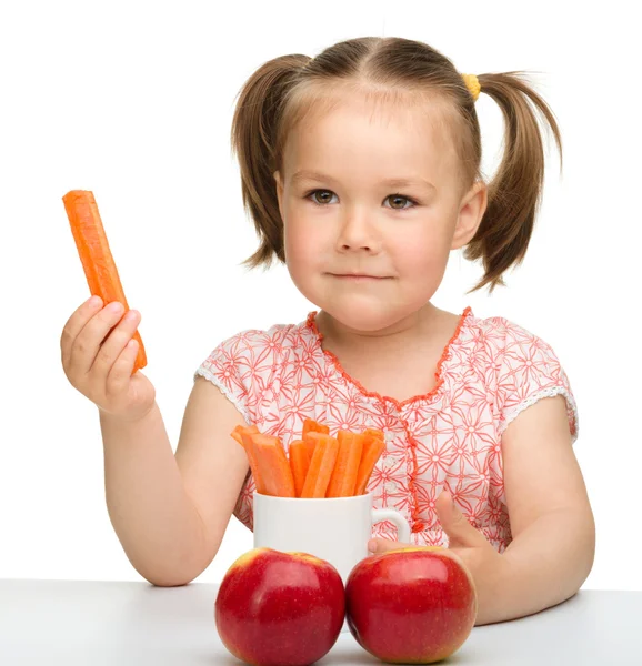 Cute little girl eats carrot and apples — Stock Photo, Image
