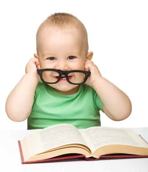 Маленький ребенок играет с книгой и очками — стоковое фото