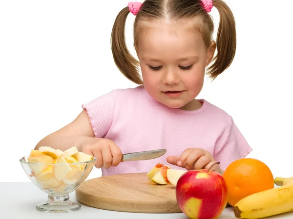 Kleines Mädchen schneidet Früchte für Salat — Stockfoto