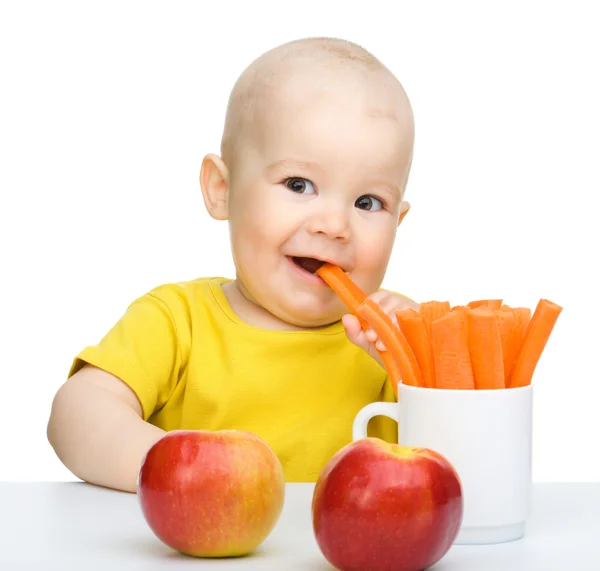 Bonito menino come cenoura e maçãs — Fotografia de Stock