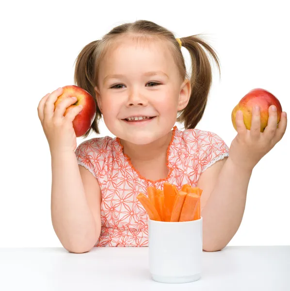 Söt liten flicka äter morot och äpplen — Stockfoto