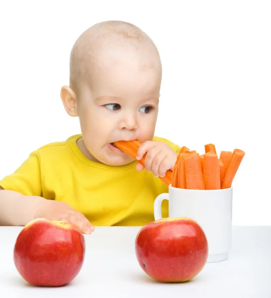 Schattige kleine jongen eet wortel en appels — Stockfoto