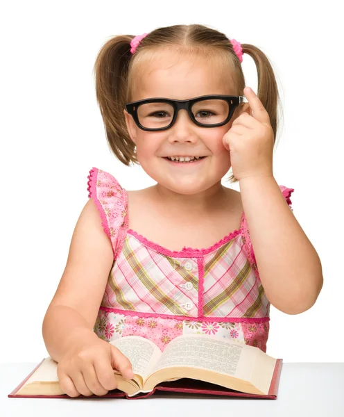 Klein meisje is spiegelen over pagina's van een boek — Stockfoto