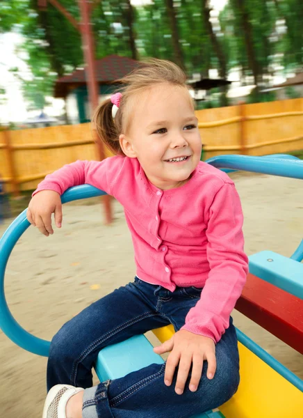 Carina bambina sta cavalcando su allegro-go-round — Foto Stock