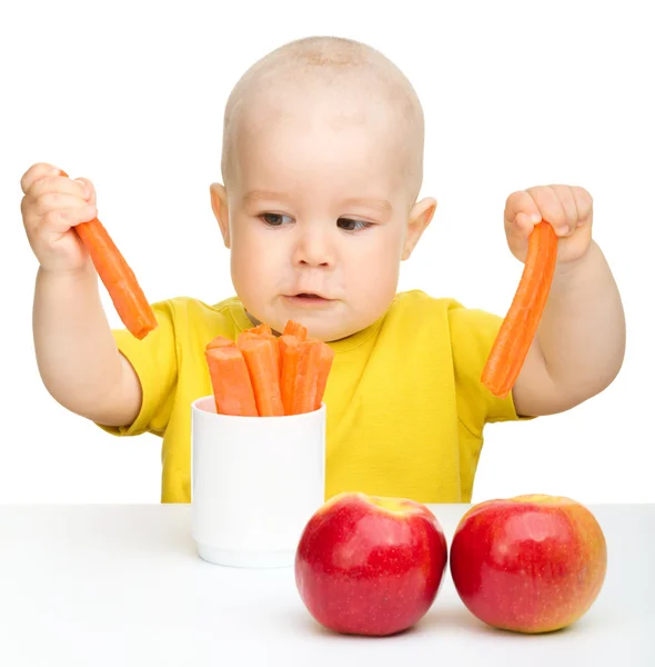Kleiner Junge zieht Karotte aus einer Tasse — Stockfoto