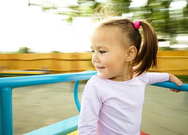 かわいい女の子はメリーゴーランドに乗っています。 — ストック写真