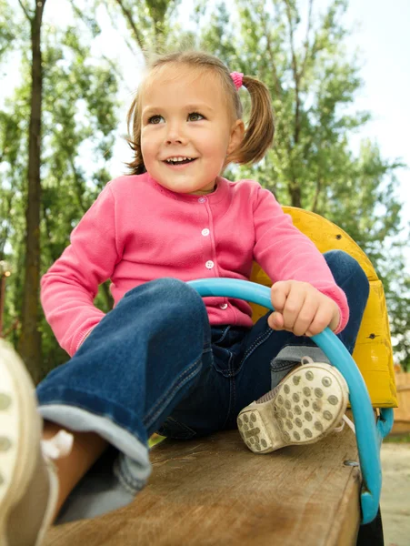 Cute little girl is swinging on see-saw — Stock Photo, Image