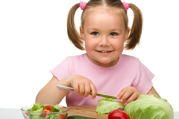 Pikkutyttö leikkaa porkkanaa salaatiksi. — kuvapankkivalokuva