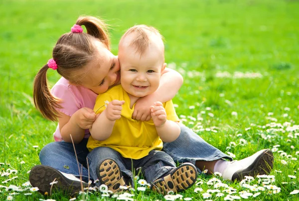 Dos niños están sentados en el prado verde Imágenes de stock libres de derechos