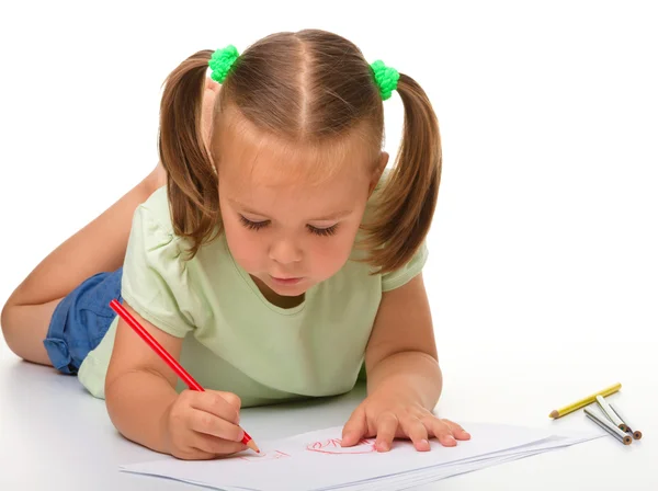 Kleines Mädchen zeichnet, während es auf dem Boden liegt — Stockfoto