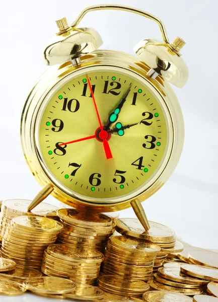 El tiempo es dinero - marcación del reloj y monedas de oro Fotos de stock libres de derechos