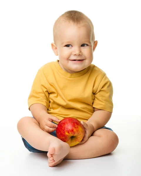 Веселый маленький мальчик с красным яблоком — стоковое фото