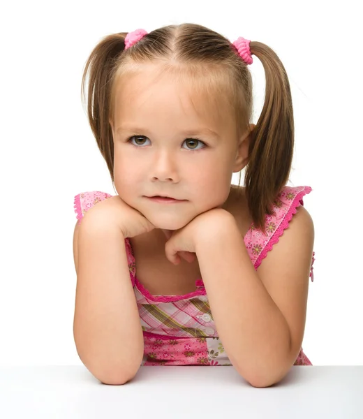 Милая маленькая девочка сидит за столом — стоковое фото