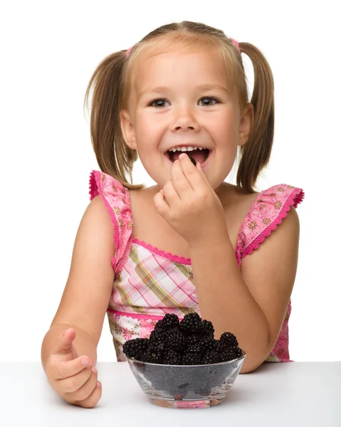 Cheerful little girl is eating blackberry — Stock Photo, Image
