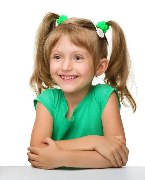 Glückliches kleines Mädchen sitzt am Tisch — Stockfoto