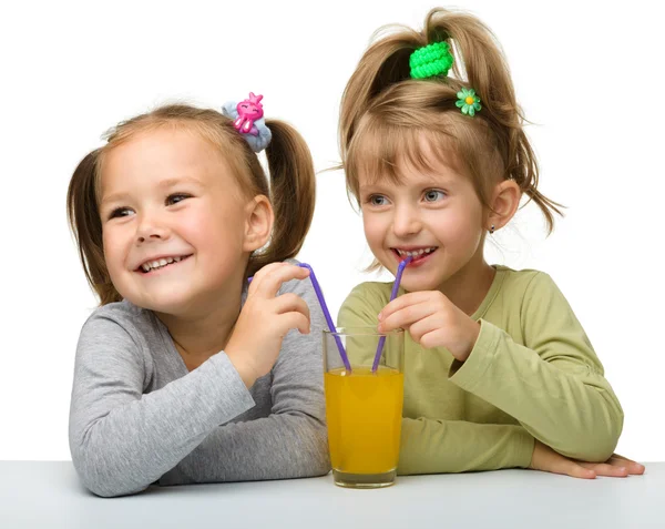 Dvě malé holčičky jsou pít pomerančový džus — Stock fotografie