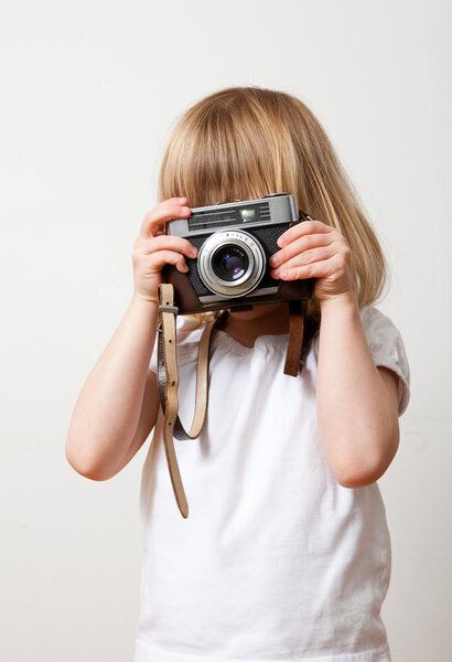 Little girl with an old camera. Studio shot.