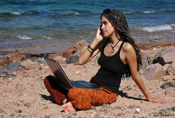 Dziewczyna z laptopa i telefon na plaży — Zdjęcie stockowe