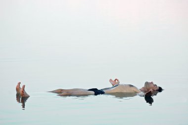 Man floating in a glassy water of dead sea clipart