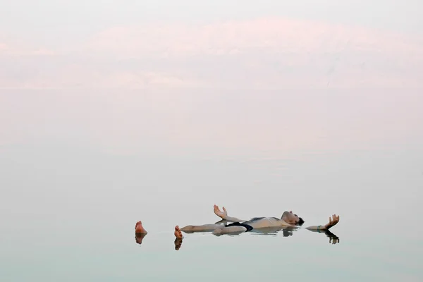 Чоловік плаває у скляній воді мертвого моря — стокове фото