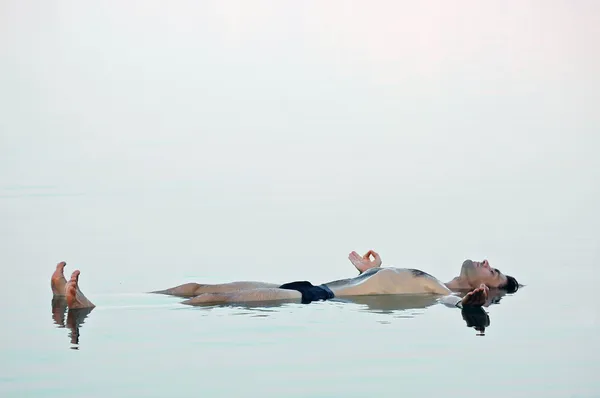 Hombre flotando en un agua cristalina de mar muerto —  Fotos de Stock