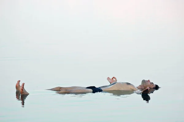 Homem flutuando em uma água vítrea de mar morto Imagens Royalty-Free