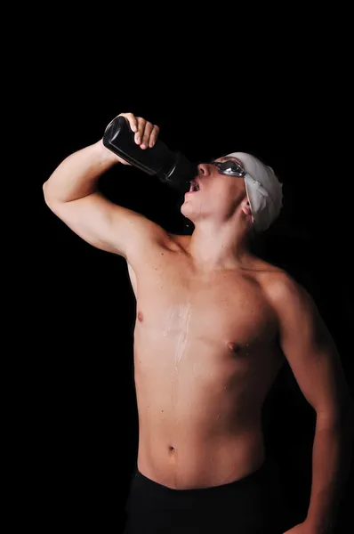 Male swimmer drinking water isolated in black — Stock Photo, Image