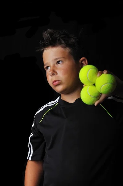 Tenis niño sosteniendo bolas aisladas en negro — Foto de Stock
