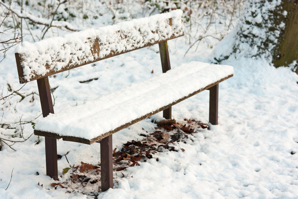 Park bench under pack of snow