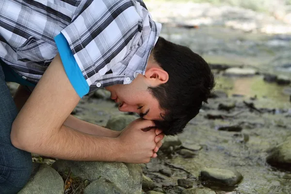 Hombre rezando por Creek —  Fotos de Stock