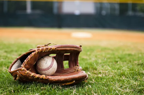 Oude honkbal en handschoen op veld — Stockfoto