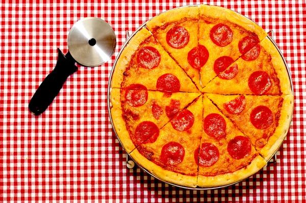 Pizza entera de pepperoni en rodajas con cortador —  Fotos de Stock