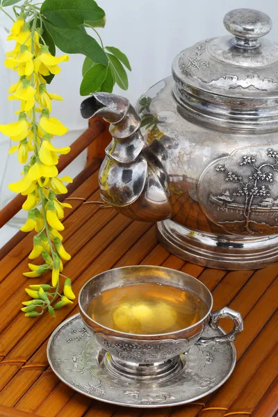 Green tea in a cup, flowers, yellow acacia on a bamboo tray — Stock Photo, Image