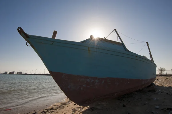 Заброшенная лодка на пляже с солнцем — стоковое фото