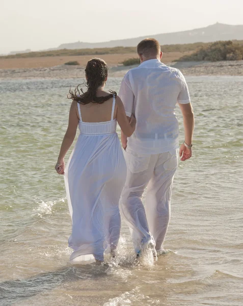 Jeunes mariés marchant sur une plage tropicale — Photo