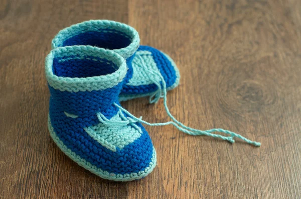 Knitted handmade baby's bootees on wood floor — Stock Photo, Image
