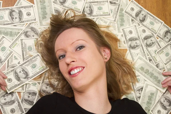 Молодая женщина с головой, лежащей на долларах — стоковое фото