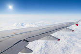 Flugzeugflügel über Wolken und Sonne