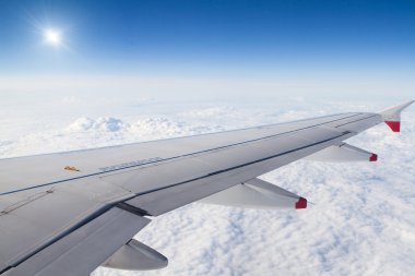 Airplane wing above the clouds and sun clipart