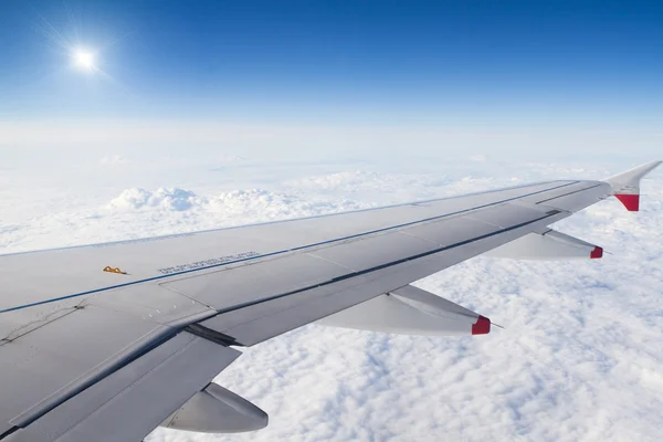 Крыло самолета над облаками и солнцем — стоковое фото