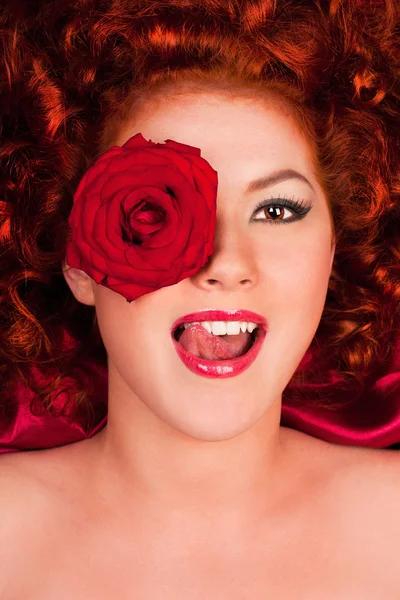 Red-haired woman with a flower on a background of curtains