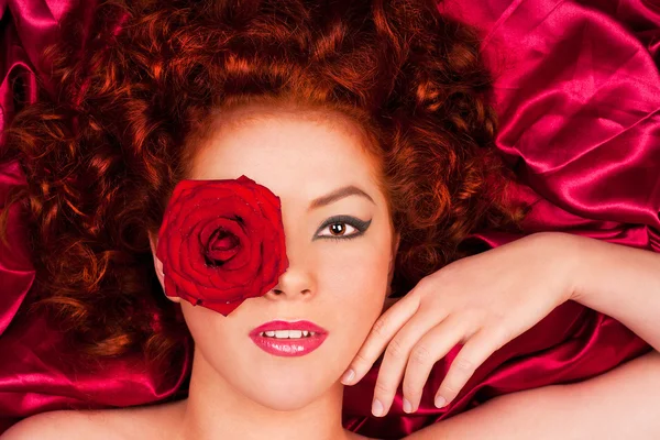 Rudowłosa kobieta z kwiatem na tle kurtyny — Zdjęcie stockowe